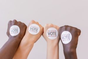 close up photo of vote stickers on people s fist